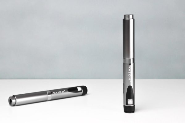 Two VAION pens are displayed against a light gray background. One VAION pen is standing upright, showcasing its sleek metallic silver design and branding. The other pen is lying horizontally on the white surface, partially visible.